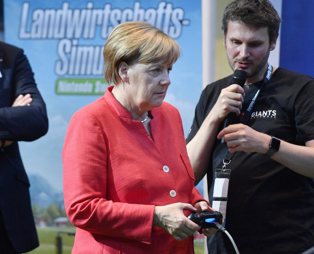 German chancellor Angela Merkel plays an agriculture simulation game during the Gamescom fair for computer games in Cologne, Germany, Tuesday, Aug. 22, 2017. The leading European trade fair for digital gaming culture is the meeting point for global companies from the entertainment industry and the international gaming community. (AP Photo/Martin Meissner)